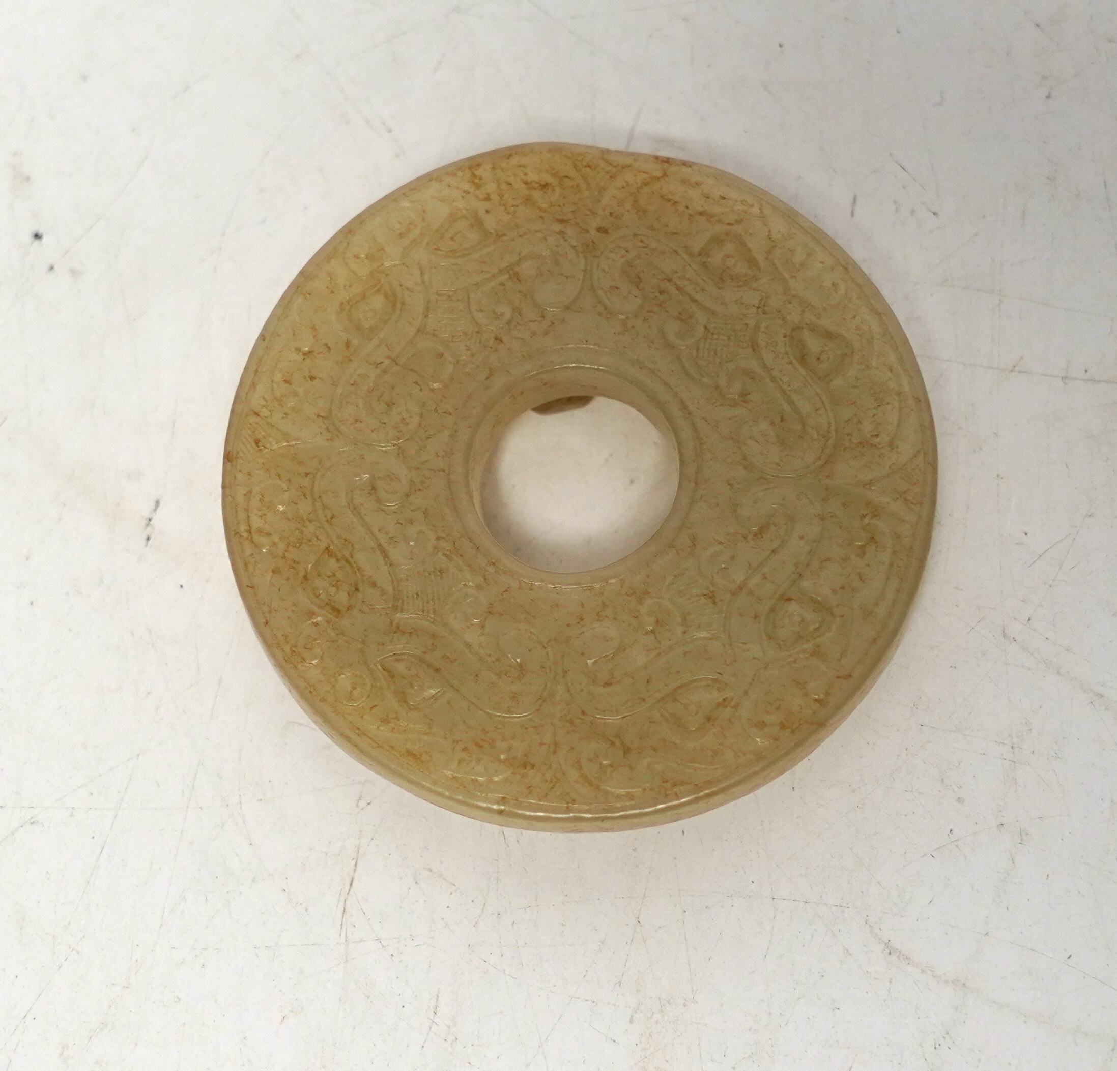 An 18th century Chinese mottled jade bi disc, decorated with two carved chilong, 5.8cm diameter